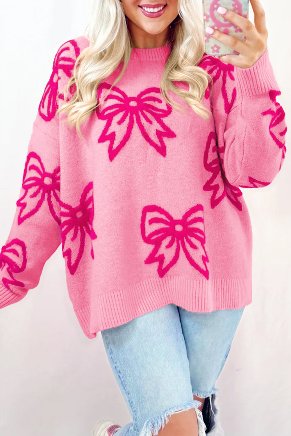 Feminine pink bow print loose fit sweater with drop shoulders and round neckline.