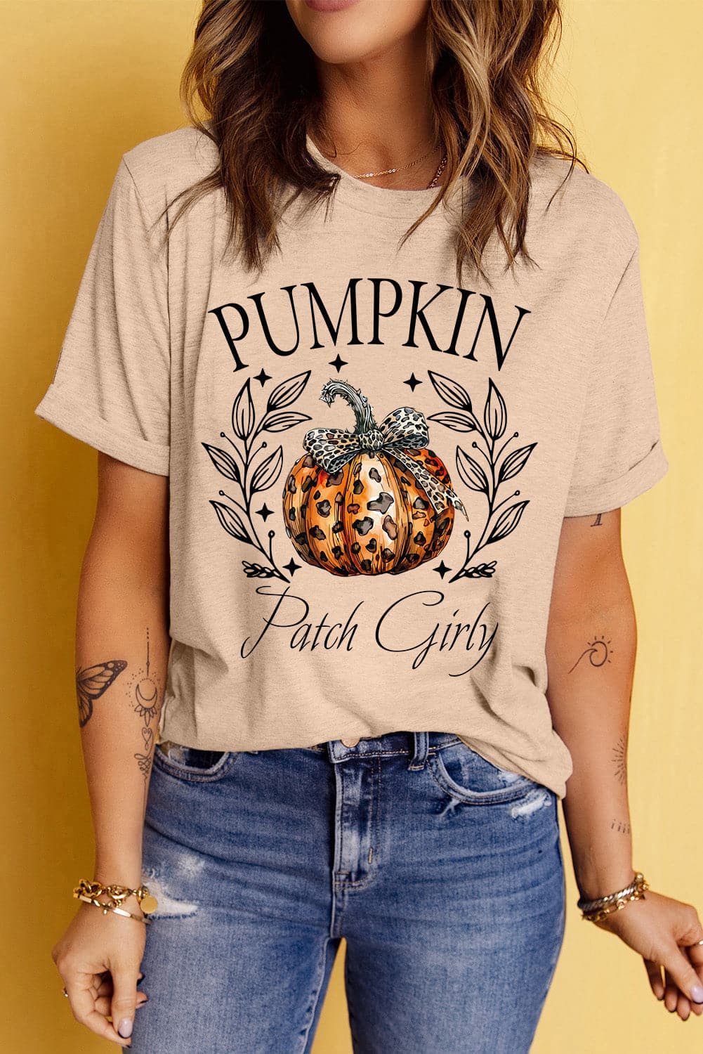 Autumn pumpkin graphic tee with round neck and short sleeves, styled with jeans.