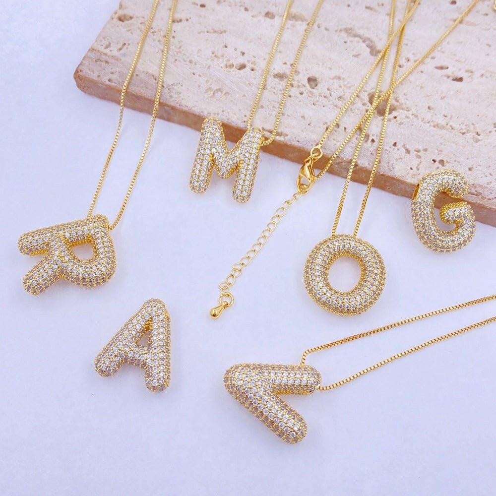 Zircon-encrusted gold letter pendants on gold chains.