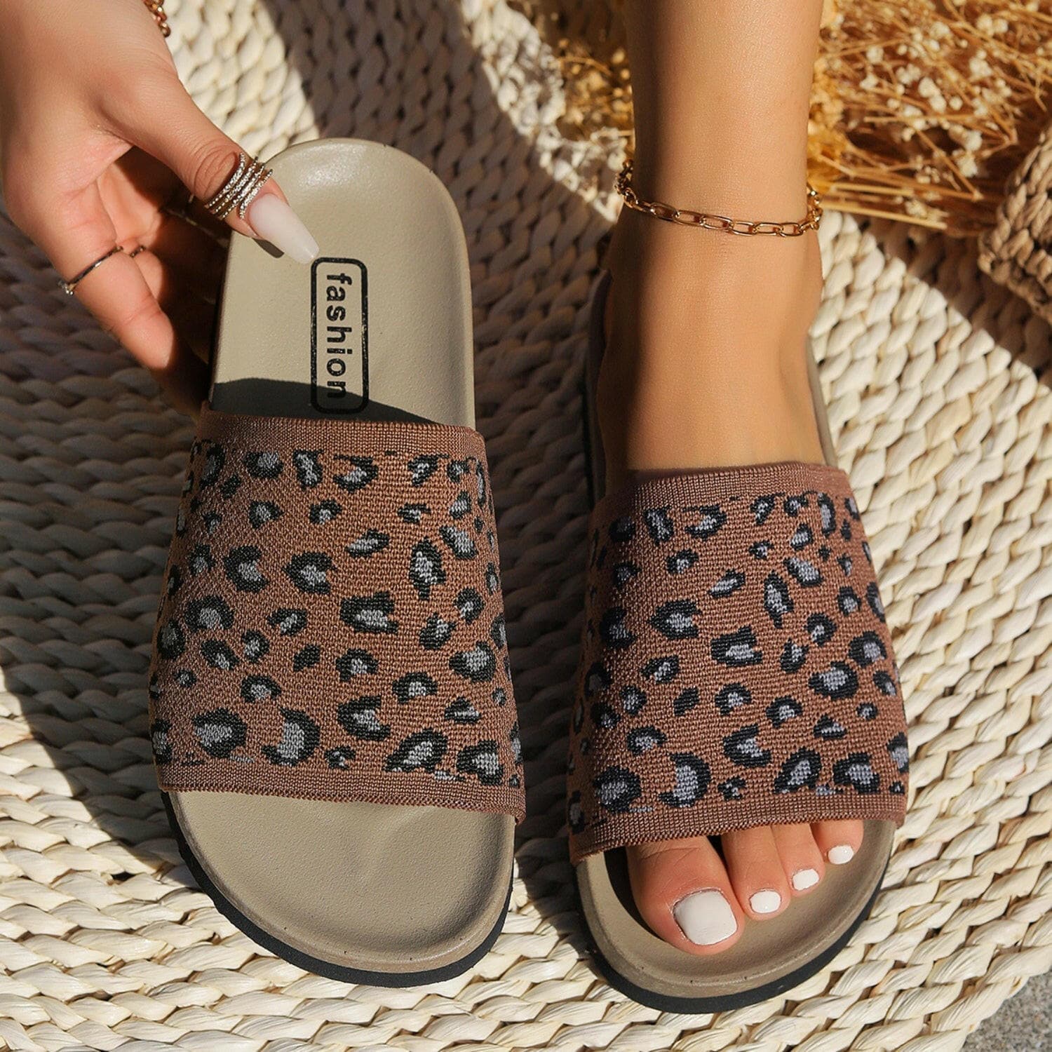 Leopard print open toe flat sandals on woven mat.