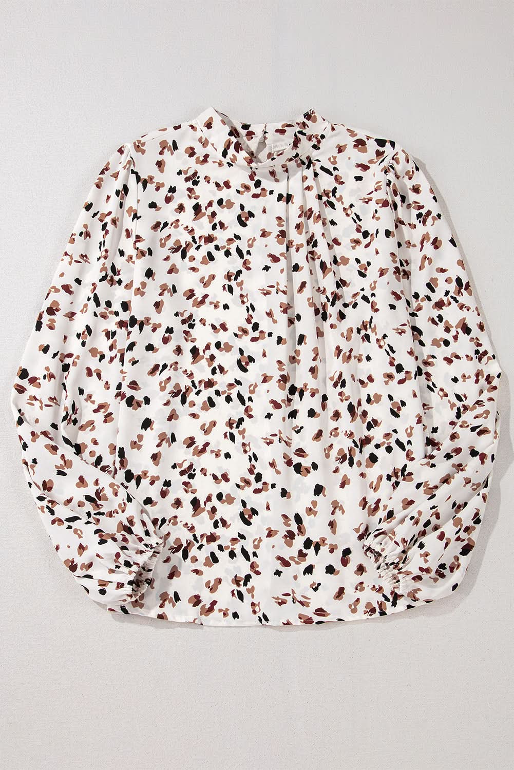 White leopard print lantern sleeve blouse with mock neck and pleated design.