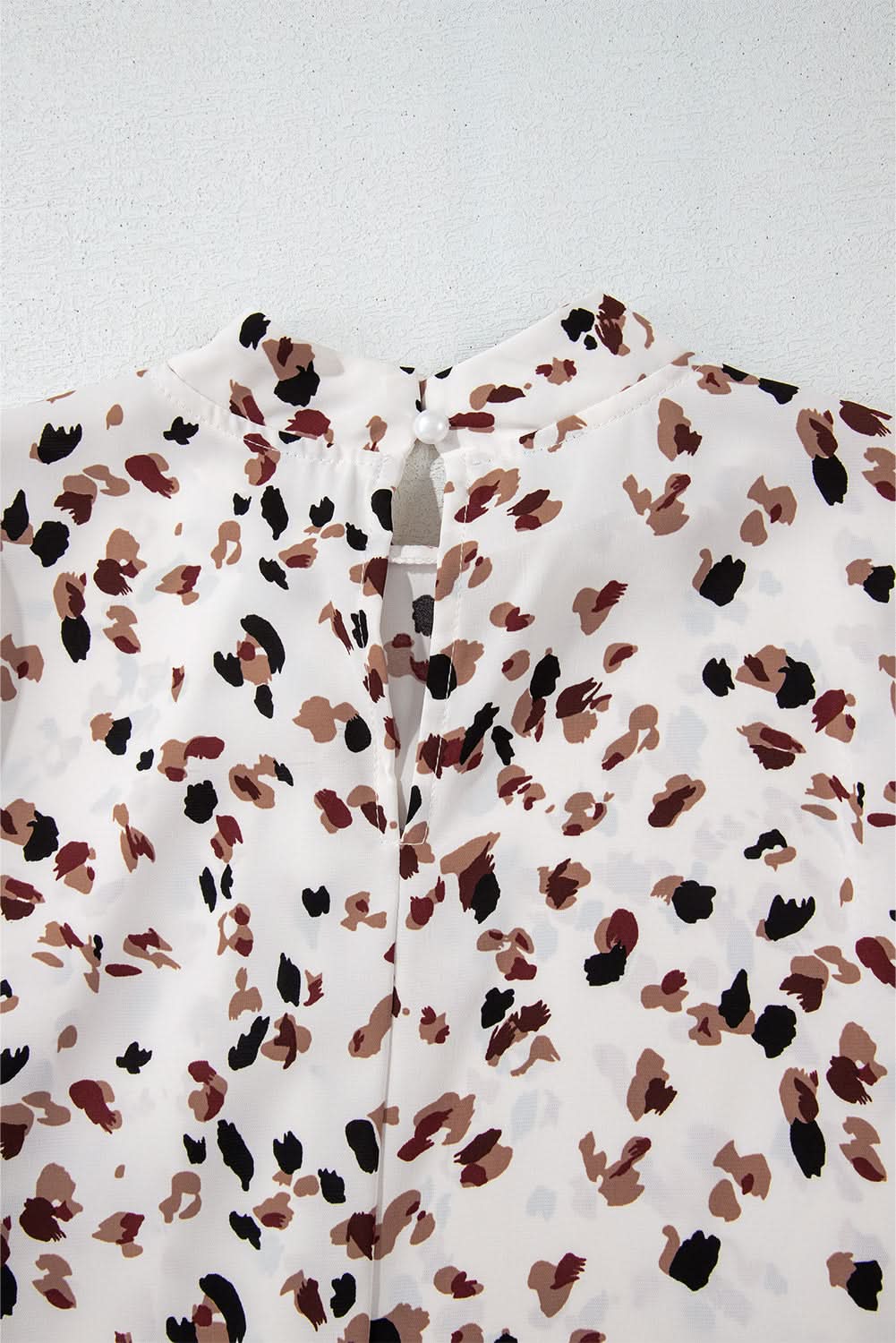 White leopard print blouse with lantern sleeves and mock neck.