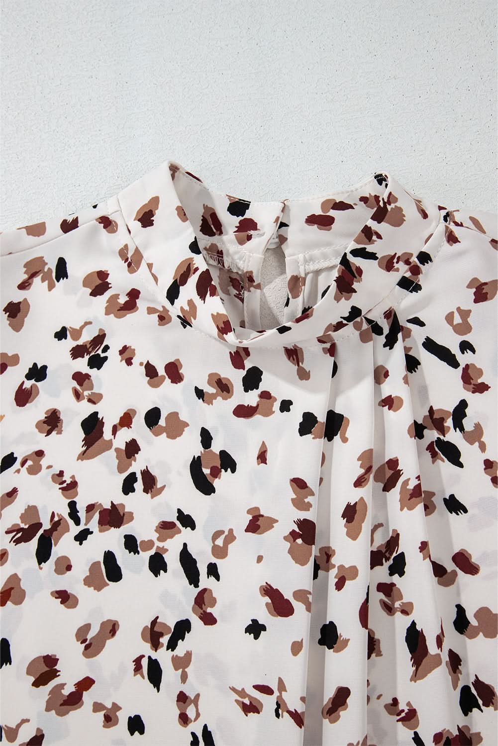 White leopard print lantern sleeve mock neck pleated blouse.