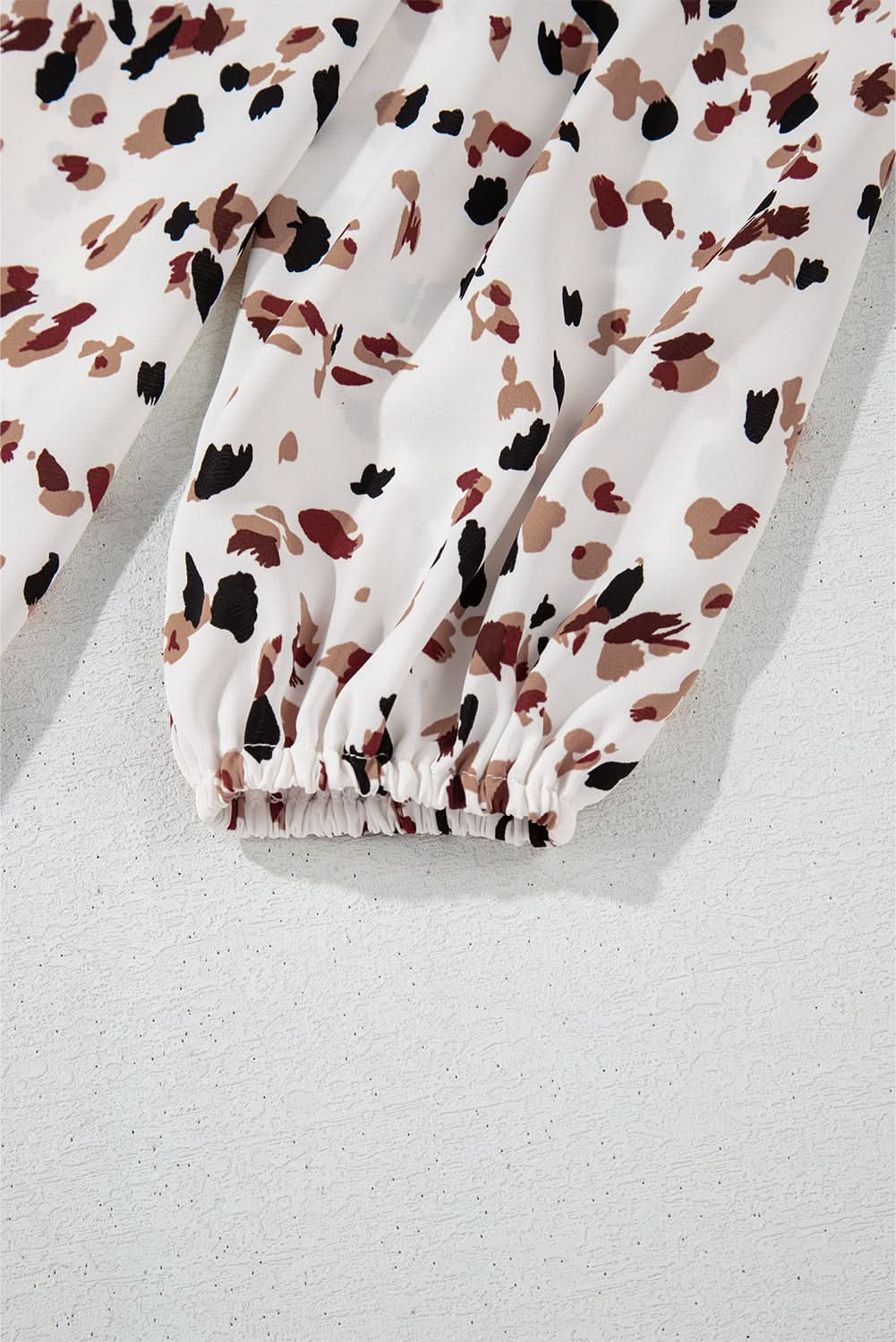 White leopard print lantern sleeve mock neck pleated blouse fabric detail.
