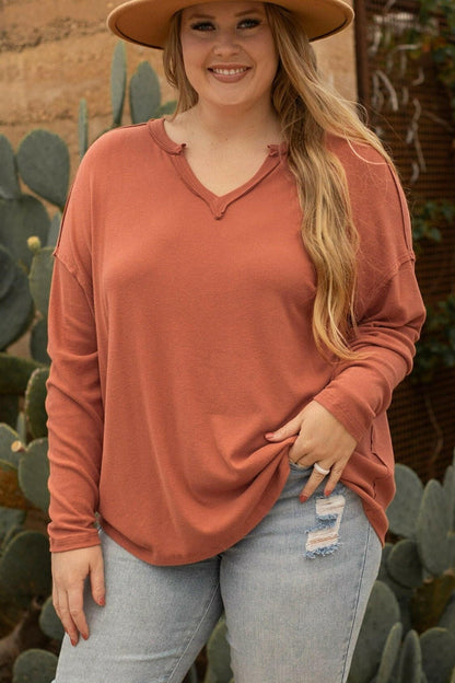 Curvy woman wearing a chic notched long sleeve tunic in a casual outdoor setting.