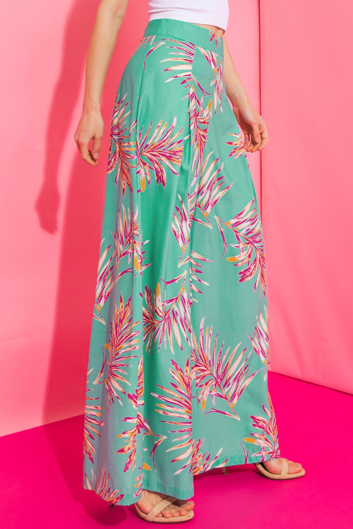 Colorful woven pants with a wide-leg design and tropical print on a pink background.