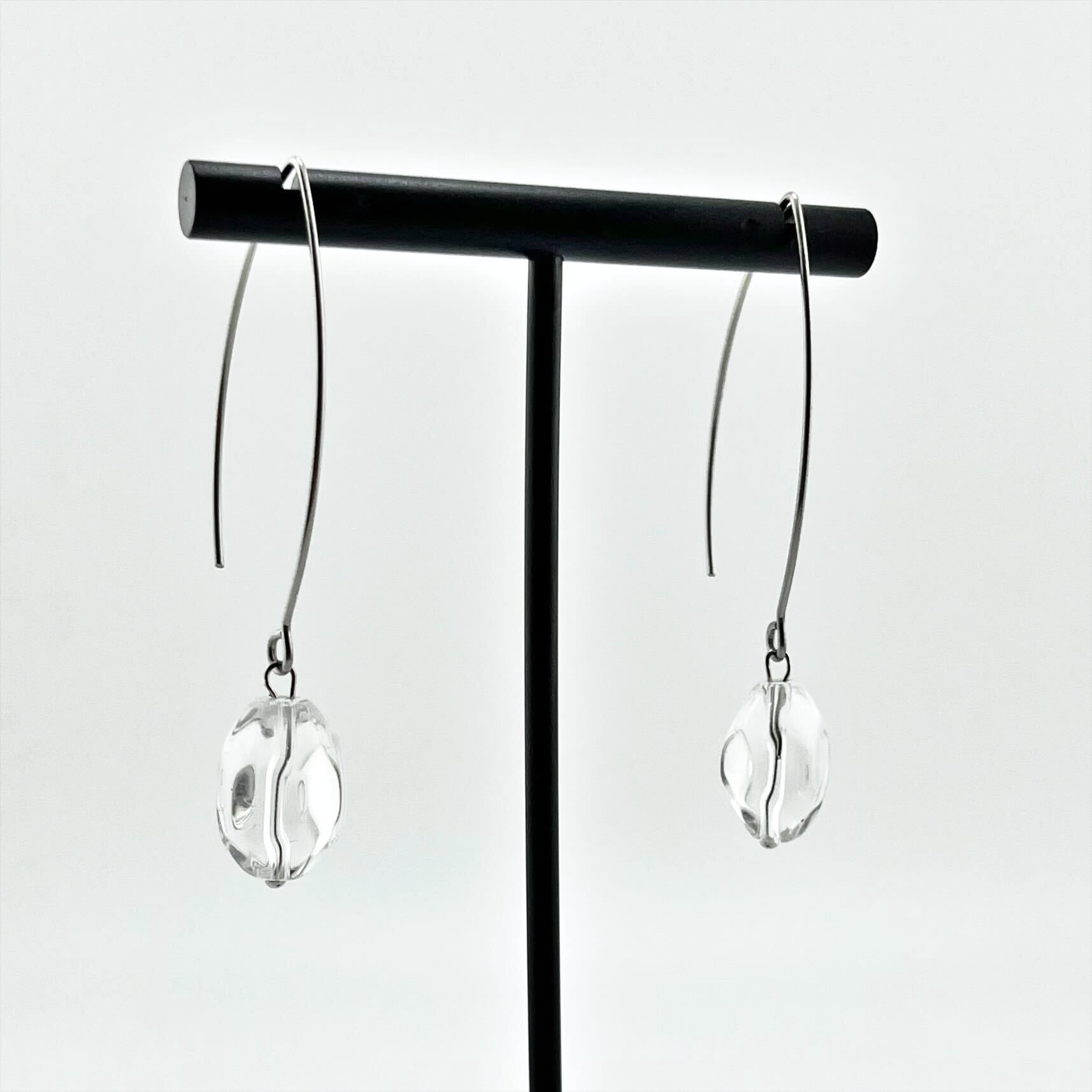 Pair of Katia Designs Small Stone Drop Earrings resting on a soft white fabric, emphasizing their delicate design and matching stone hues.