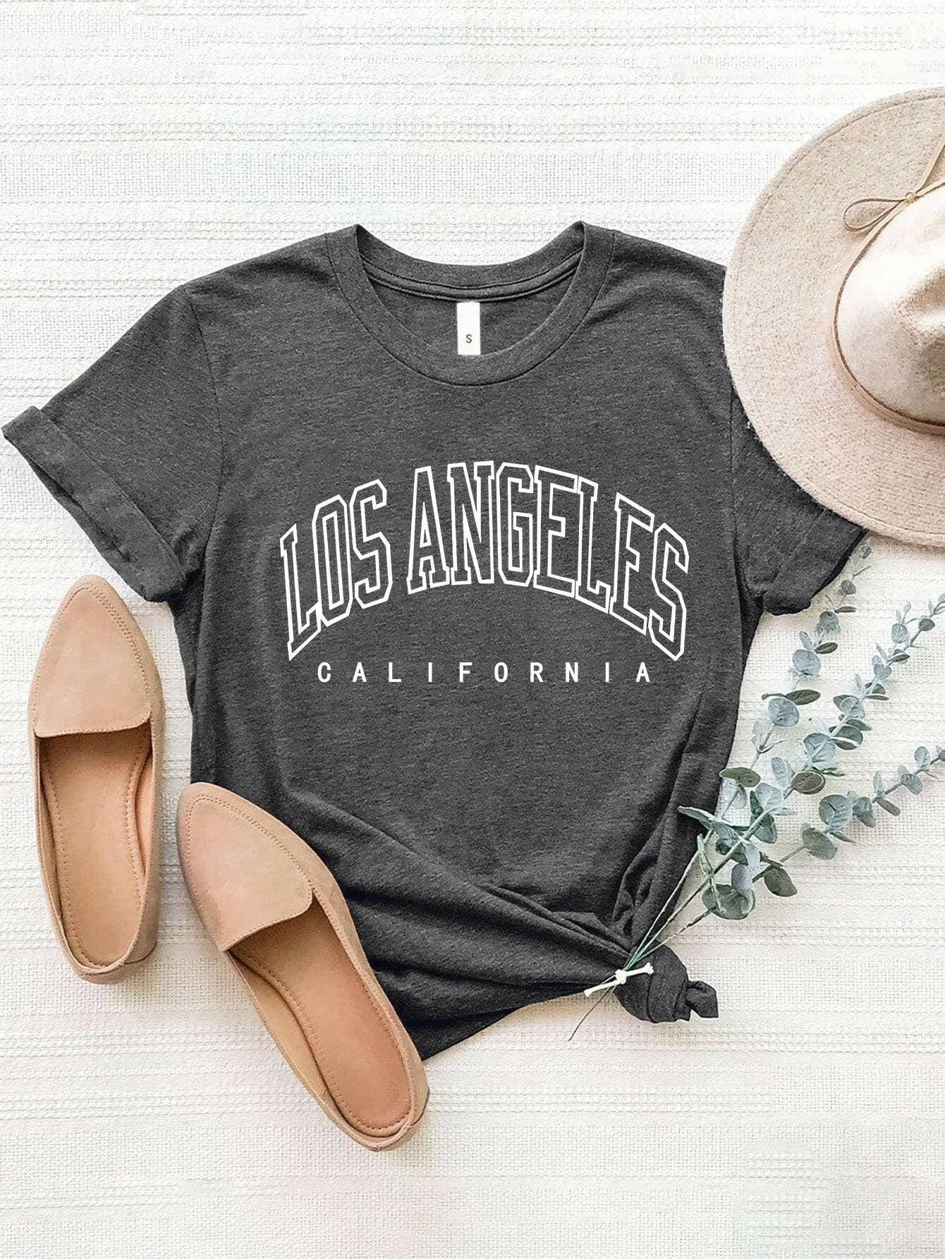 City of Angels California Round Neck TeeCity of Angels California Round Neck Tee
 Upgrade your style game with the City of Angels California Round Neck Tee, a perfect fusion of comfort and chic. This tee iLove Salve Angels California Round Neck TeeGraphic