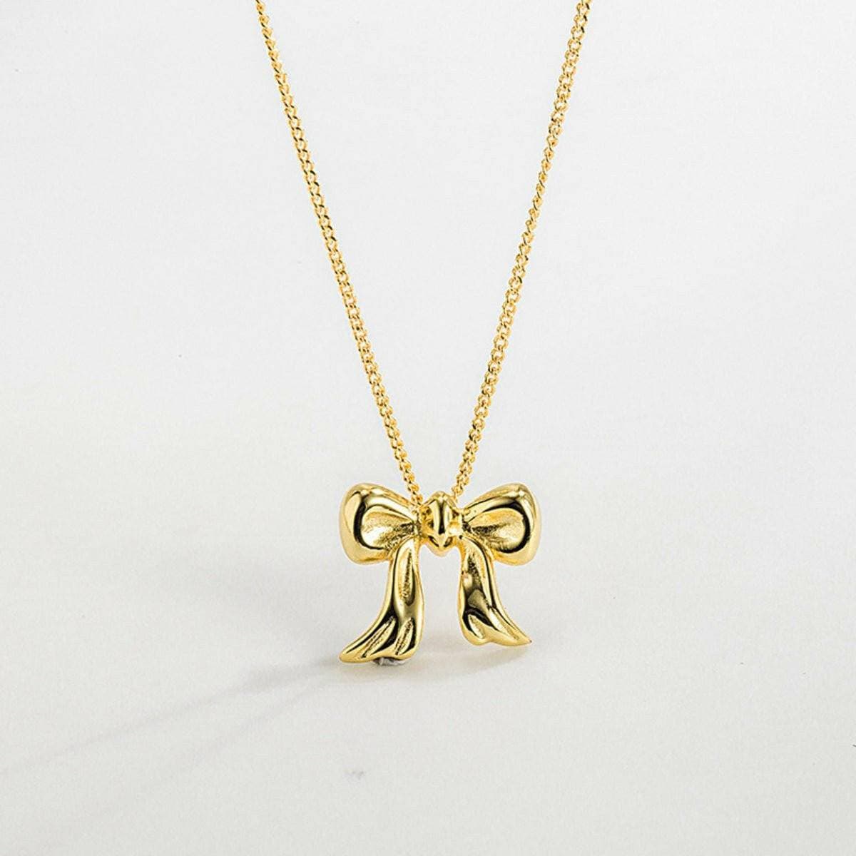 Copper bow pendant necklace with elegant design in gold plating.