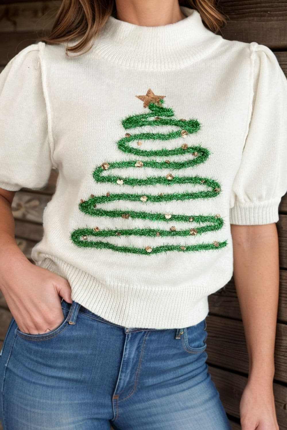 Glittering sequin pullover top with festive design and exposed seam.